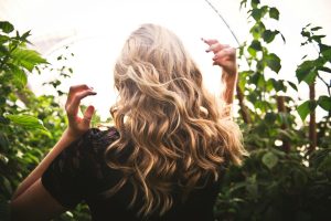 blonde haired woman standing between green plants