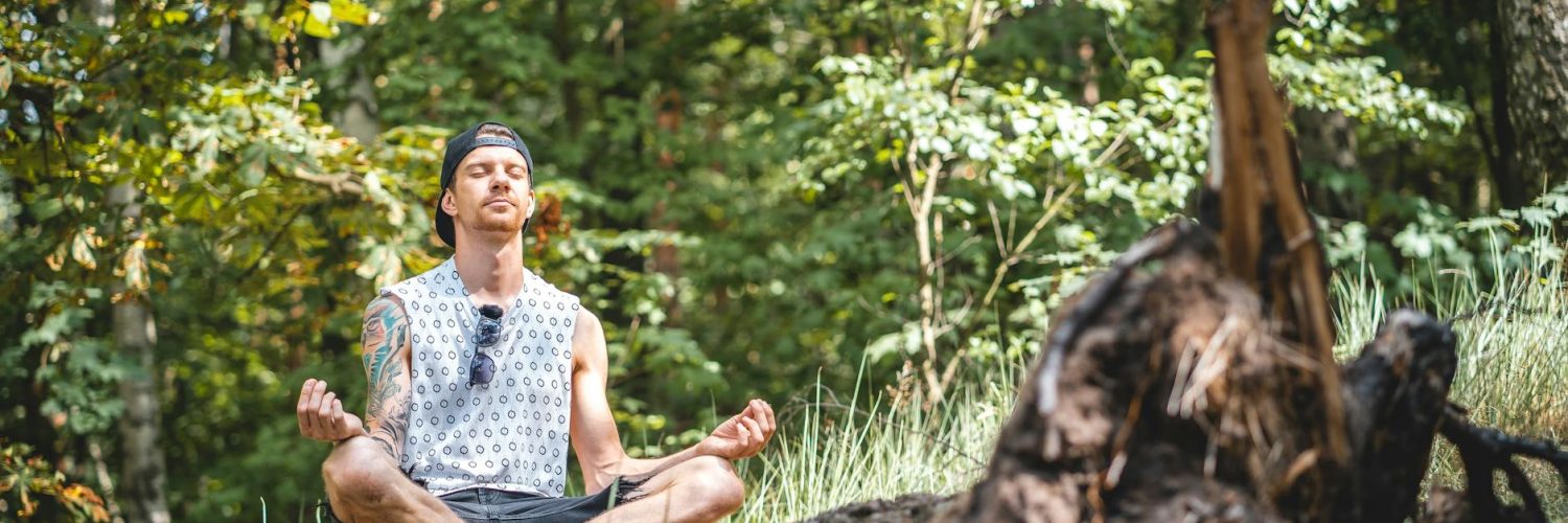 man meditating on a tree log