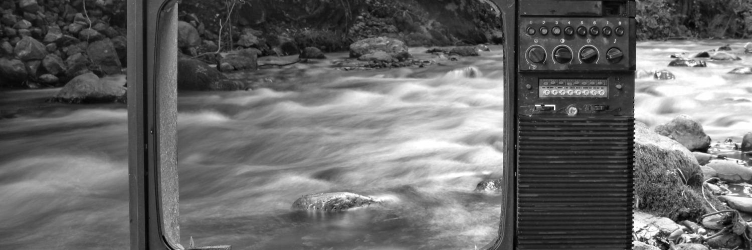 retro tv on river shore near forest